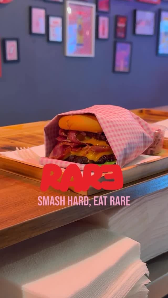 Burger dans son papier vichy posé sur le comptoir, mur de cadres en arrière-plan
